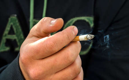 Man with cigarette in hand, smoker close up.の写真素材