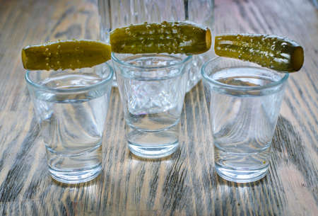 Vodka in a glass and pickled cucumber. Traditional Russian alcoholic drink with a snackの写真素材