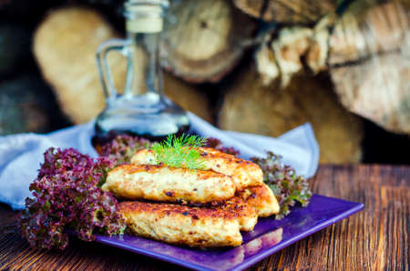 Chicken cutlets on a plate with lettuce leaves on the table close-up