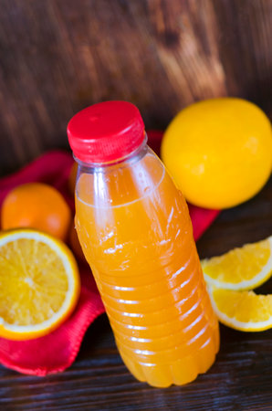 orange juice in a plastic bottle on a table with fruitsの写真素材