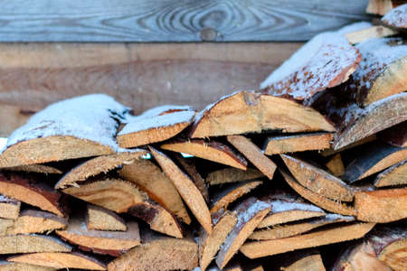 Stacked old boards under the snow. Cutting firewood for the firebox.の写真素材