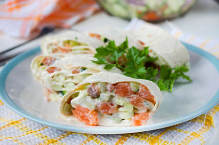Roll of salmon, avocado and cream cheese in thin pita bread on a plateの写真素材