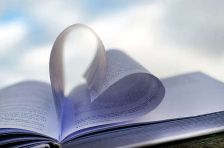 Heart from the pages of a paper book against the sky with space for textの写真素材