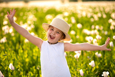 Happy little girl have a fun in white poppy fieldの写真素材