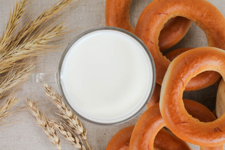 bagels, wheat ears and a glass of milk on a linen background, top viev, flat layの写真素材