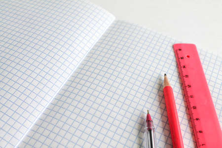 Stationery on a white background. A pen, pencil and ruler lie on a clean open sheet of a notebookの写真素材