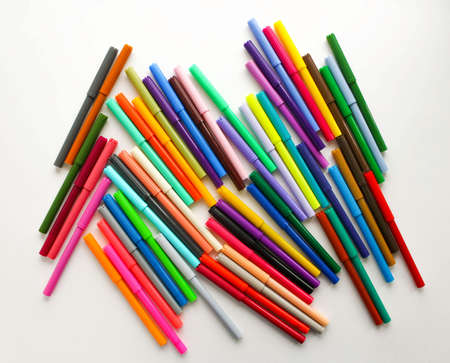 A bunch of colorful markers on a white background, top view.
