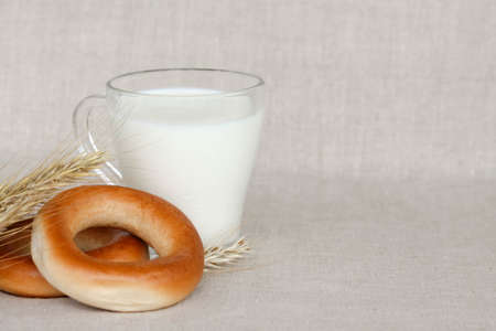 bagels, wheat ears and a glass of milk on a linen background, space for textの写真素材