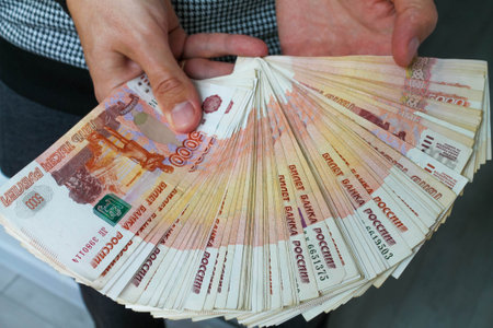 Close-up of mens hands holding a fan of Russian money in five-thousand-dollar bills.の写真素材