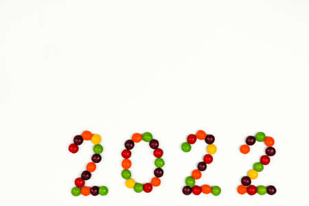 The inscription of the new year 2022 with multi-colored candy pins on a white background. The inscription is located at the bottom right, Top view.の写真素材