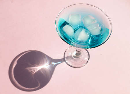 Blue cocktail with ice and on a pink background, top view, hard shadows, summer holiday conceptの写真素材