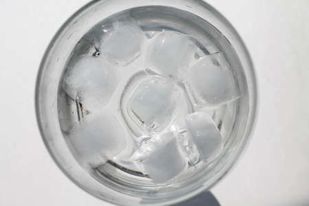 glass with cold water and ice cubes on white background, top view.の写真素材