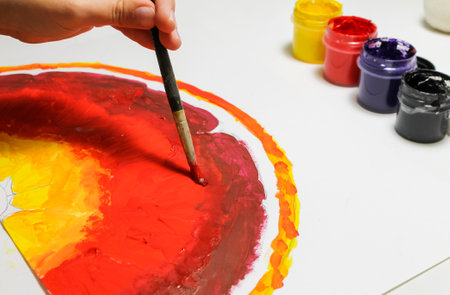 A child paints a juicy grapefruit or red orange, close-up.の写真素材