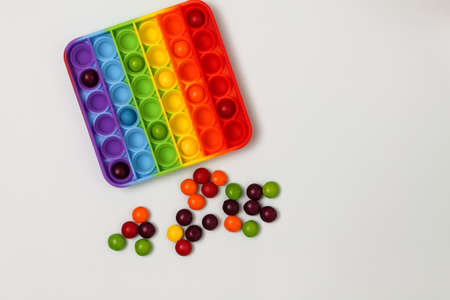 Childrens toy   with colorful candy skittles on a gray background, top viev