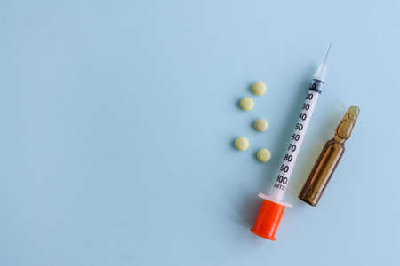 Yellow tablets, insulin syringe and ampoule on a blue background. Diabetesの写真素材