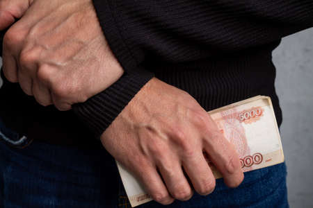 Close-up of mens hands holding a wad of Russian money with five-thousand-dollar bills. High quality photoの写真素材