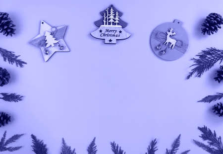 Wooden Christmas decorations, branches of thuja and pine cones on purple background, top view, flat...