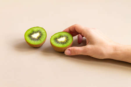 The womans hand takes half a kiwi. The concept of diet and healthy eatingの写真素材