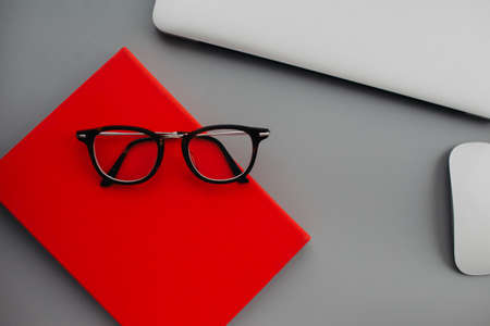 Flat lay workdesk with eyeglasses notebook and red diary on gray background. high quality photoの写真素材