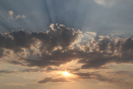 The sky at sunset, when the sun breaks through the clouds and its rays diverge in different...