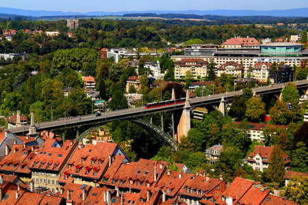 Panorama of the historic part of Bern with red-roofed houses, green parks and iron arched bridge with mountains in the backgroundの写真素材