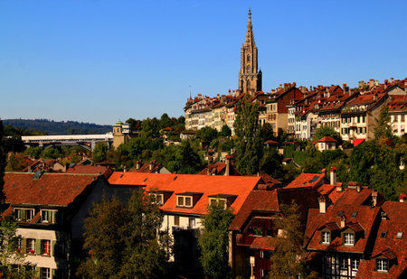 Street view of the historic part of Bern with houses with red roofs, the spire of Bern Cathedral and the bridgeの写真素材