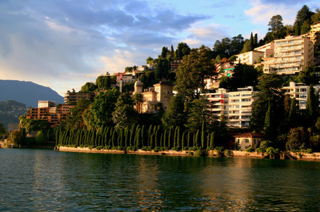 Lugano, Switzerland-03/09/2018: Photo with the view of the landscape with a hill, houses and Lake Lugano against the stormy sky in the city of Lugano, in southern Switzerlandのeditorial素材