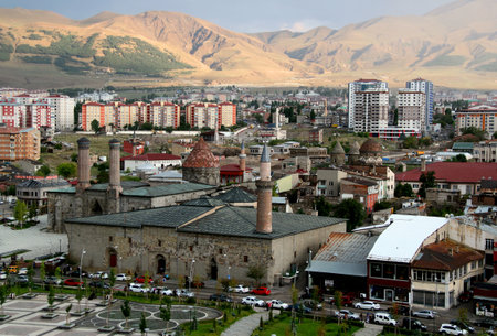 Erzurum, Turkey - August 20, 2021: Photo with the Erzurum city center with Ulu Camii mosque and Cifte Minareli Medrese against the backdrop of the sunlit mountainsのeditorial素材