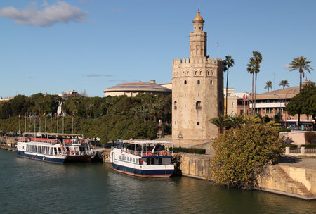 Seville, Spain - December 02, 2021: Photo with the view of the Torre del Oro Tower and the Guadalquivir River promenade with boats in the historic center of Seville, Andalusiaのeditorial素材