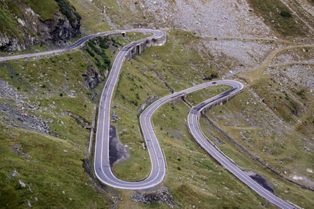 Landscape photo with view of green rocky mountains and Transfagarasan mountain road in Romania