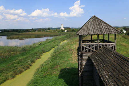 Landscape photo with a view of the lake and the tower of the Wooden Fortress against a blue sky with clouds in the village of Peresopnytsia, Rivne region in Ukraineの写真素材