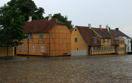 Photo with a view of yellow half-timbered buildings on a square during the rain in the historic...