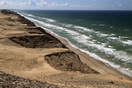 Landscape photo with a view of the North Sea coast and sand dunes against a blue sky with clouds near the Rubjerg Knude lighthouse in Denmarkの写真素材