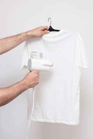 Manual garment steamer T-shirt steam on a white backgroundの写真素材