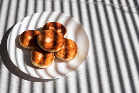cheesecakes on a white plate on a table in the sunの写真素材