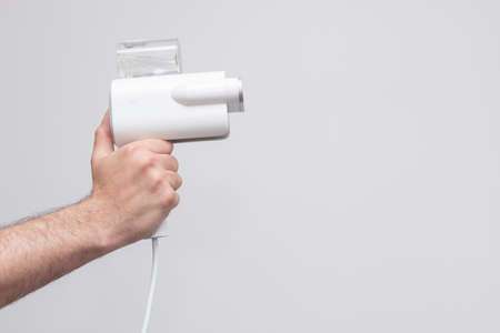 Handheld mini steamer in hand on white background