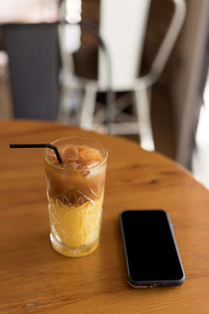 coffee cocktail juice with coffee and a smartphone on the table in a coffee shop. close up.の写真素材