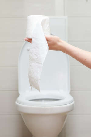 a roll of toilet paper on the background of a white toilet bowl in the toiletの写真素材