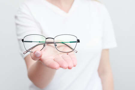 woman holding close-up glasses in her hand on a white backgroundの写真素材