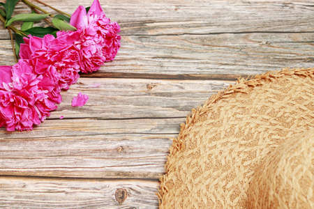 pink peonies and straw hat on a wooden backgroundの写真素材