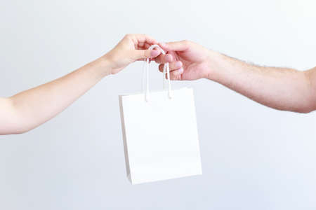 white craft bag in the hands of a man and a woman close-up
