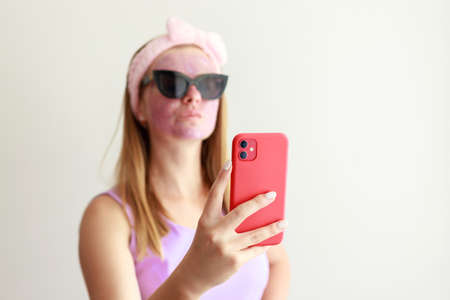 woman in a cosmetic mask on her face takes a selfie on a white backgroundの写真素材