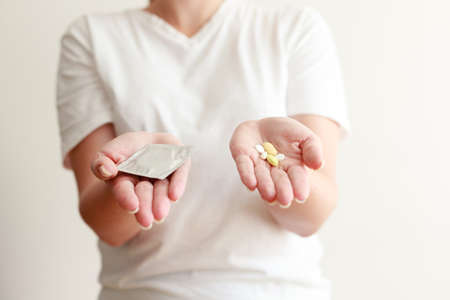 woman holding condom and contraceptivesの写真素材
