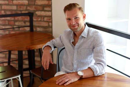 Handsome young smiling man driving a car. Happy male driver smiling while sitting in car with open front window.の写真素材