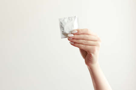 disposable condom in hand on white background close-upの写真素材