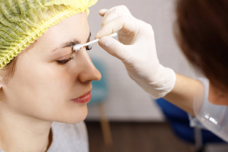 beautician applying botox on the eyebrows of a woman close-upの写真素材