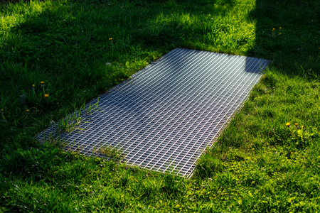 Close-Up of an Iron Sewer Grate on a Lawn: Urban Infrastructure and Stormwater Management