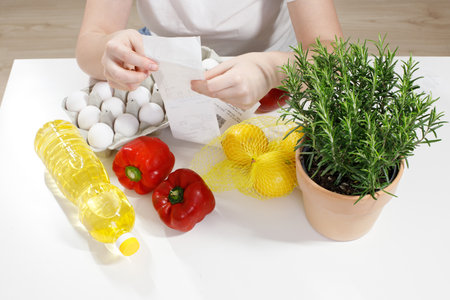 woman checks purchases in a receipt from the store. food on the tableの写真素材