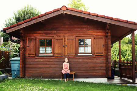 girl sitting near a summer house in the gardenの写真素材