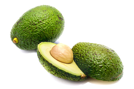 Whole avocado (Persea americana, alligator pear) and its halves with a stone isolated on white...